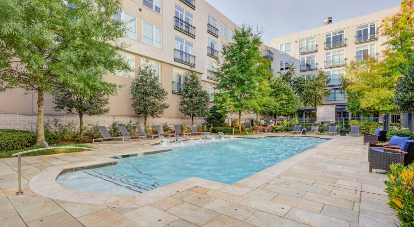 Shimmering resort-style pool Outdoor swimming pool at The Porter Brewers Hill apartments in Baltimore, MD, featuring lounge chairs and trees.
