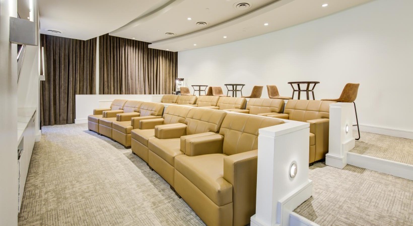 The essence of exceptional living Theater at The Porter Brewers Hill apartments in Baltimore, MD, featuring large comfortable chairs and a screen.