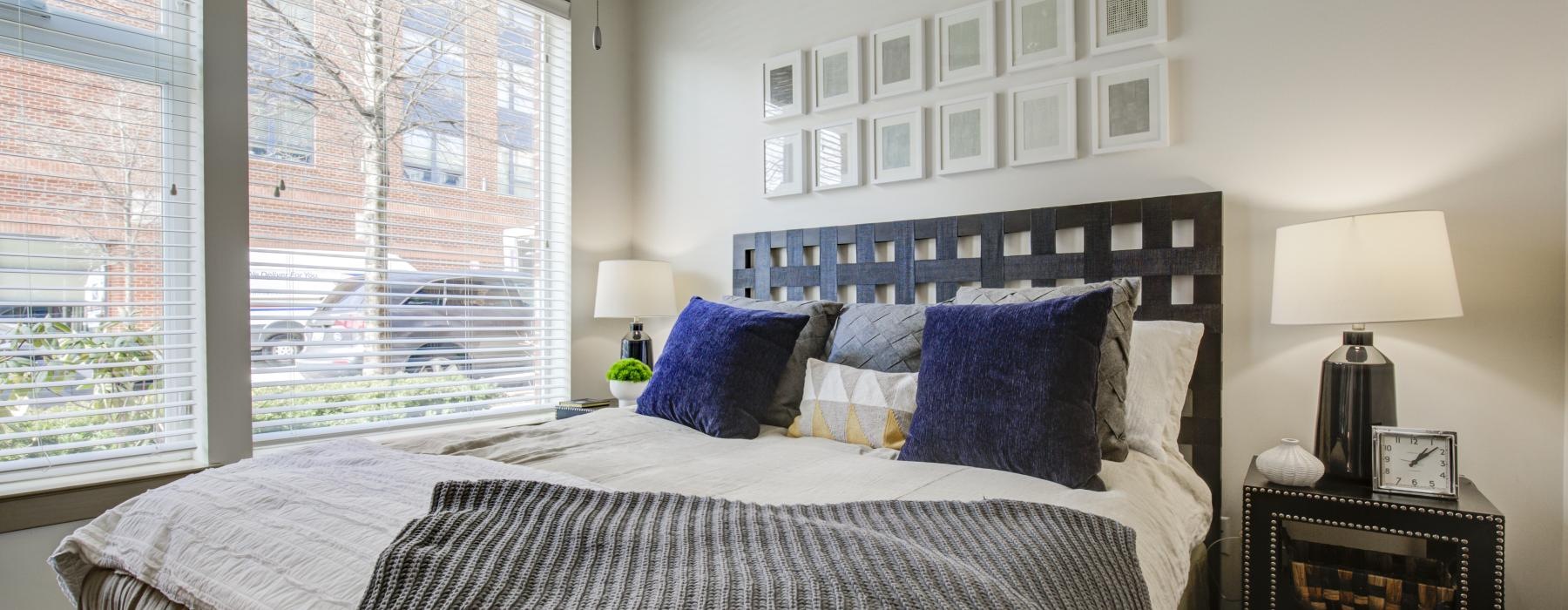 a bed with a blue and white comforter in a room with a window